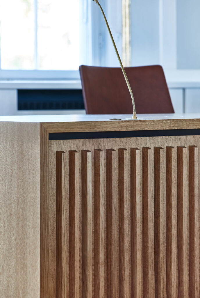 Front på byrådsbord med svævende udtryk og vertikale affasede lister – Tobleroneformet profil