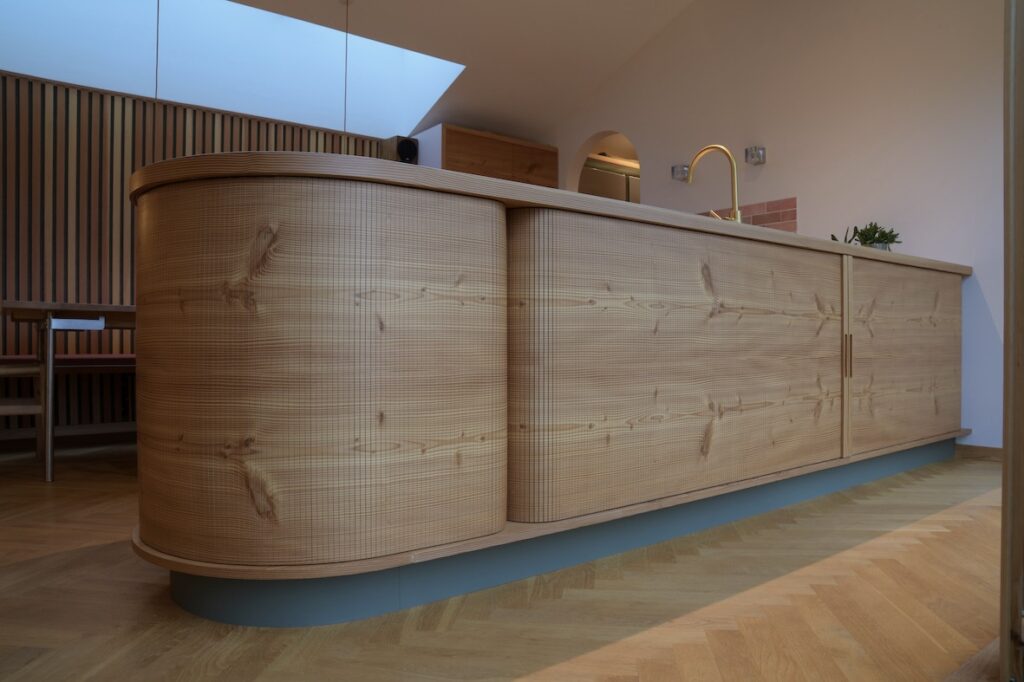 Køkkenø i douglastræ med vandret kørende jalousilåger og buede hjørner – specialdesignet løsning