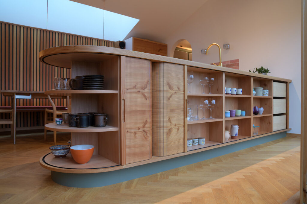 Køkkenø i douglastræ med vandret kørende jalousilåger og buede hjørner – specialdesignet løsning