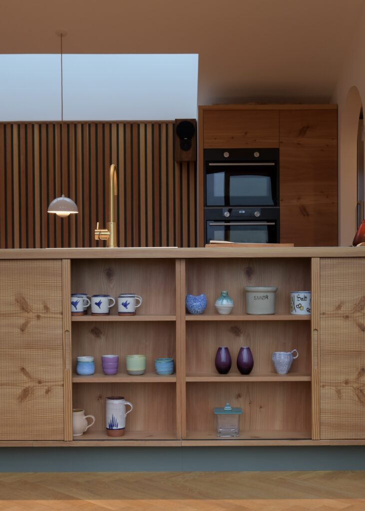 Køkkenø i douglastræ med vandret kørende jalousilåger og buede hjørner – specialdesignet løsning